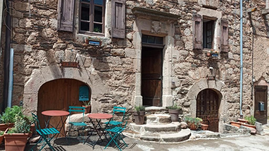 um edifício de pedra com cadeiras e mesas em frente em The Tavern em Castelnau-Pégayrols