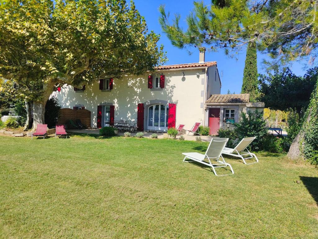 a house with two lawn chairs in the yard at Gîte Soleïado in Eyragues