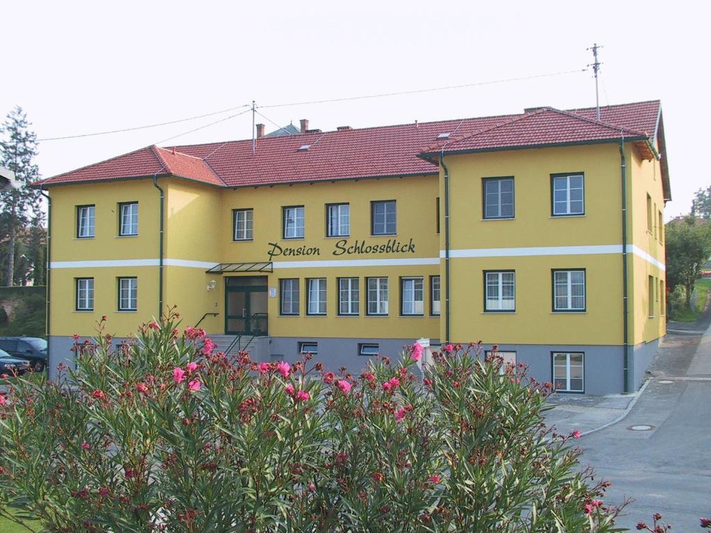 un bâtiment jaune avec un toit rouge dans l'établissement Pension Schlossblick, à Nebersdorf