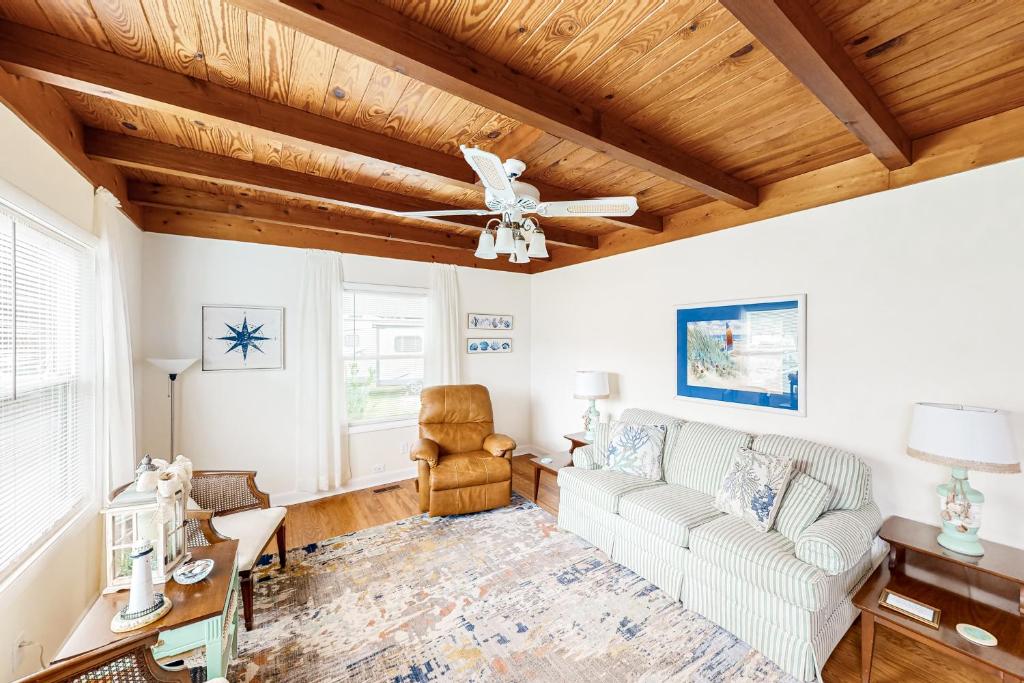 a living room with a ceiling fan and a couch at Ginny's Coastal Cottage in Oak Island