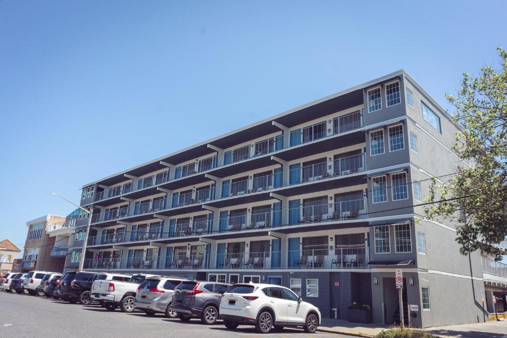 een groot gebouw met auto's geparkeerd op een parkeerplaats bij Admiral on Baltimore in Rehoboth Beach