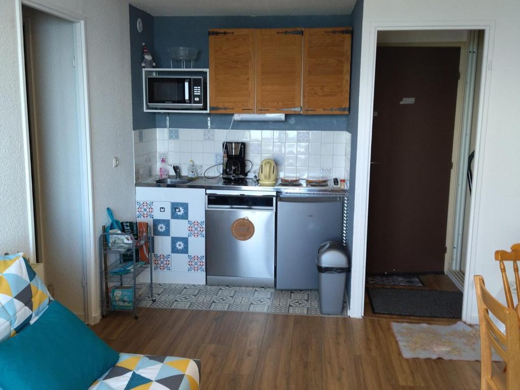 une petite cuisine avec une cuisinière et un micro-ondes dans l'établissement Appartement 2 pièces confortable, au pied des pistes, proche commerces, avec balcon et équipements modernes - FR-1-557-124, à Les Adrets