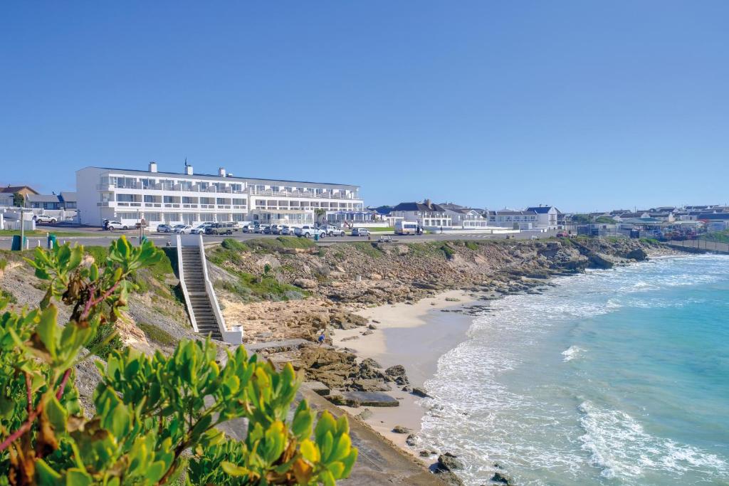 Blick auf den Strand mit Hotel und Meer in der Unterkunft Arniston Spa Hotel in Arniston