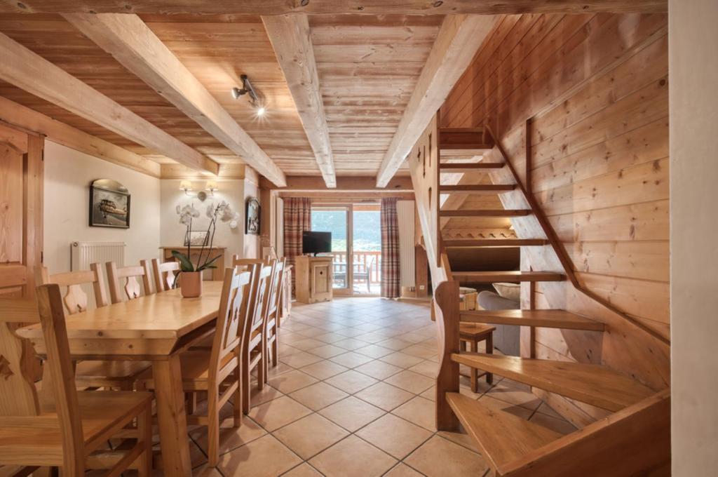 a dining room with a wooden staircase and a table and chairs at Appartement Ecrin 426 in Tignes