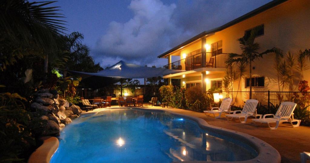 a swimming pool in front of a house at night at Mission Reef Resort in Mission Beach