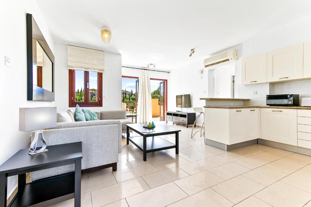 een keuken en een woonkamer met een bank en een tafel bij 2 bedroom Apartment Anatoli with communal pool, Aphrodite Hills Resort in Kouklia