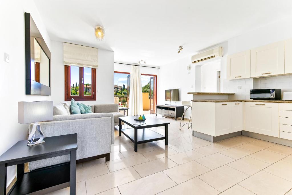 Il dispose d'une cuisine et d'un salon avec un canapé et une table. dans l'établissement 2 bedroom Apartment Anatoli with communal pool, Aphrodite Hills Resort, à Kouklia