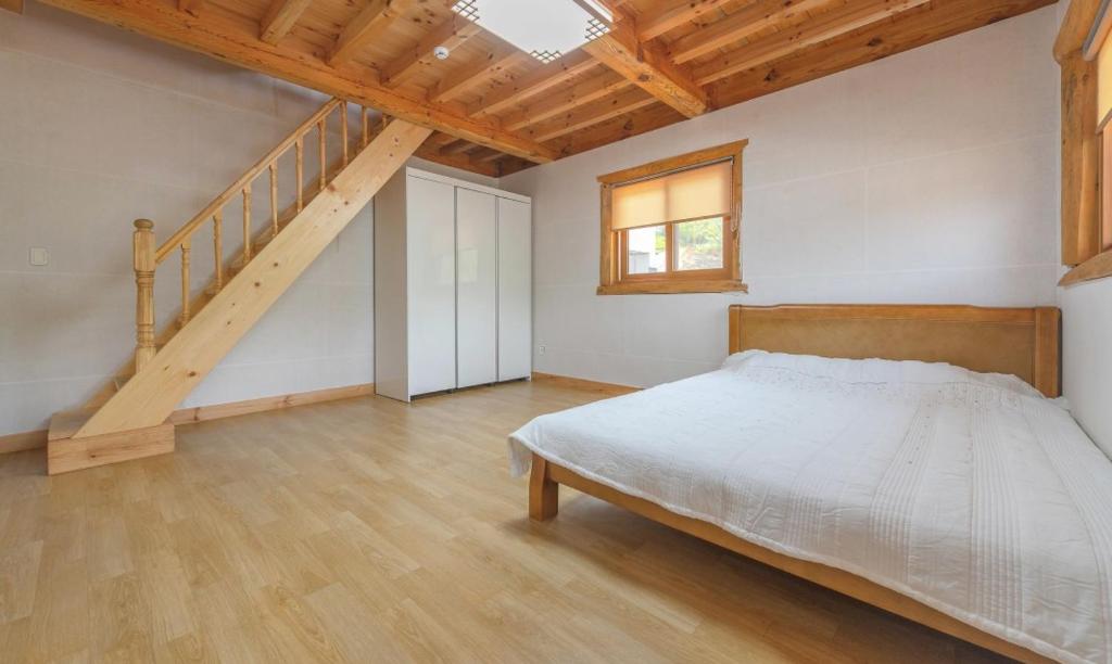a bedroom with a bed and a staircase at Saranbang Pension in Gapyeong