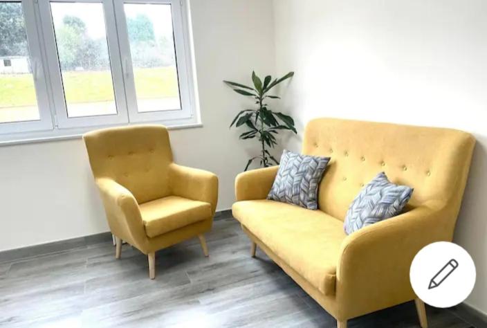 sala de estar con sofá amarillo y silla en La Cucada, en O Vicedo