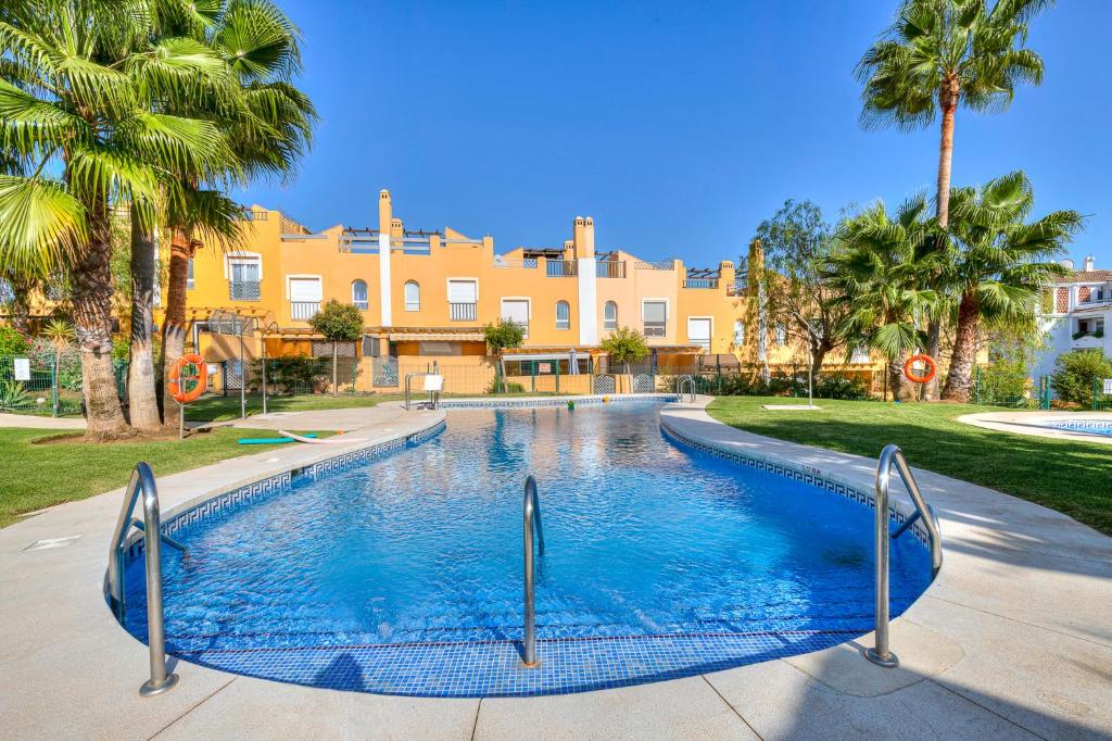 une piscine bordée de palmiers et un bâtiment dans l'établissement Maison Arlette, à Mijas