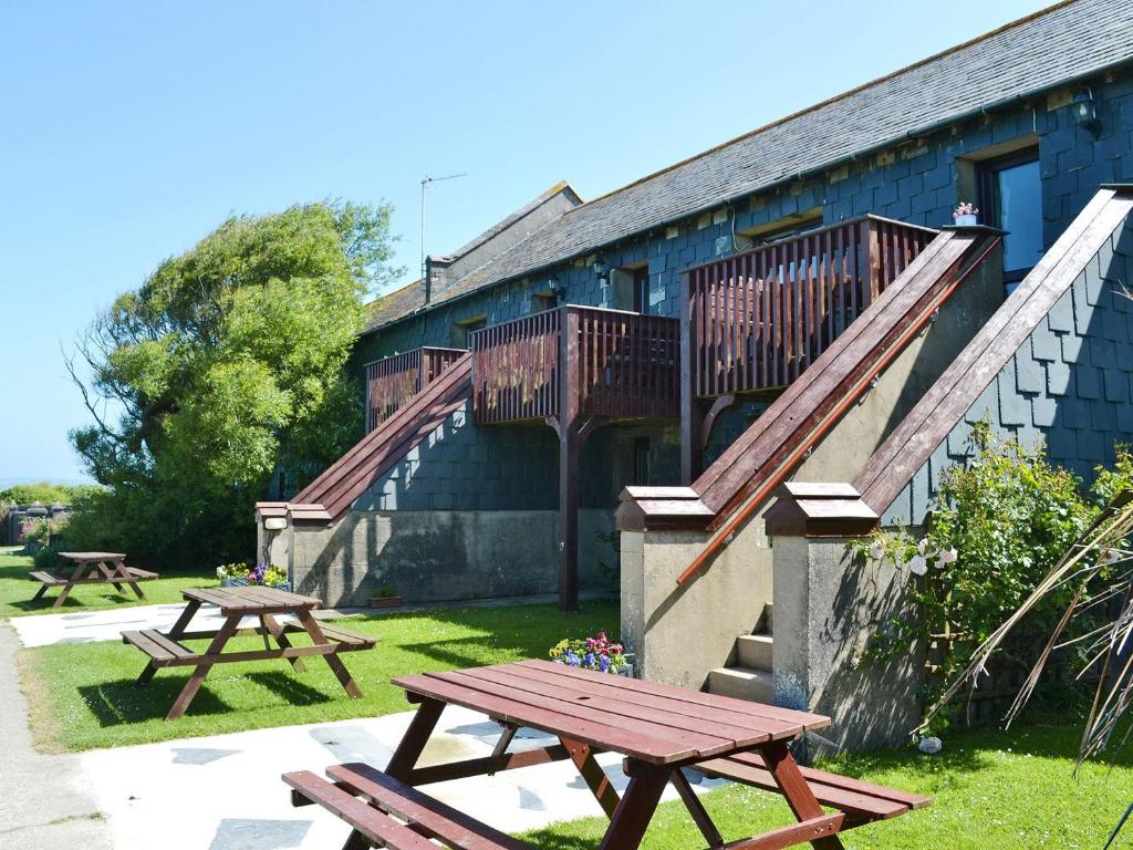 un par de mesas de picnic frente a un edificio en Barn Cottage - Ukc2682, en Poundstock