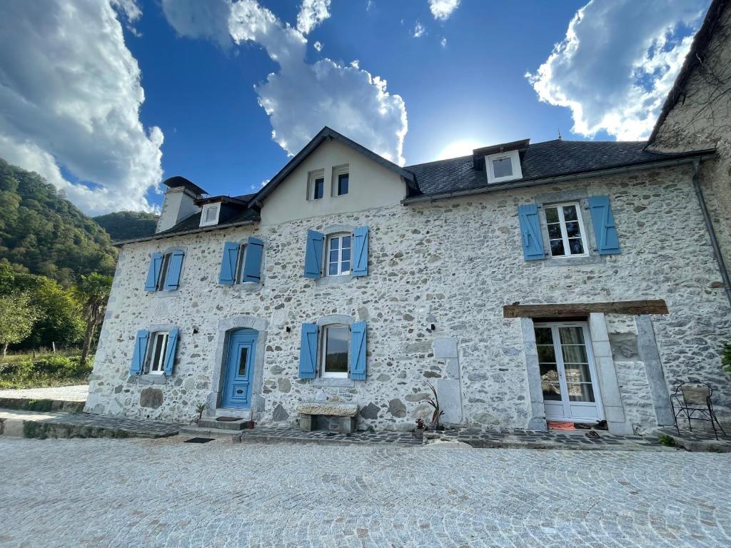 Une vieille maison en pierre avec des volets bleus sur une rafale dans l'établissement Le Val Éveillé 4 étoiles - maison de maître de 1773, à Arudy