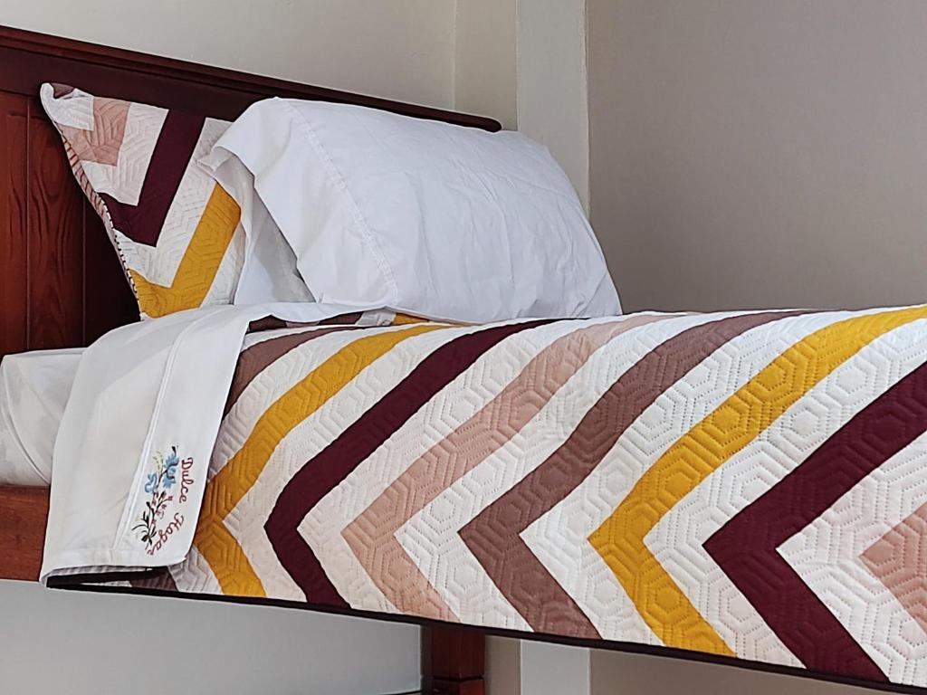 ein Bett mit einer bunten Bettdecke und Kissen darauf in der Unterkunft Dulce Hogar 02 in Loja