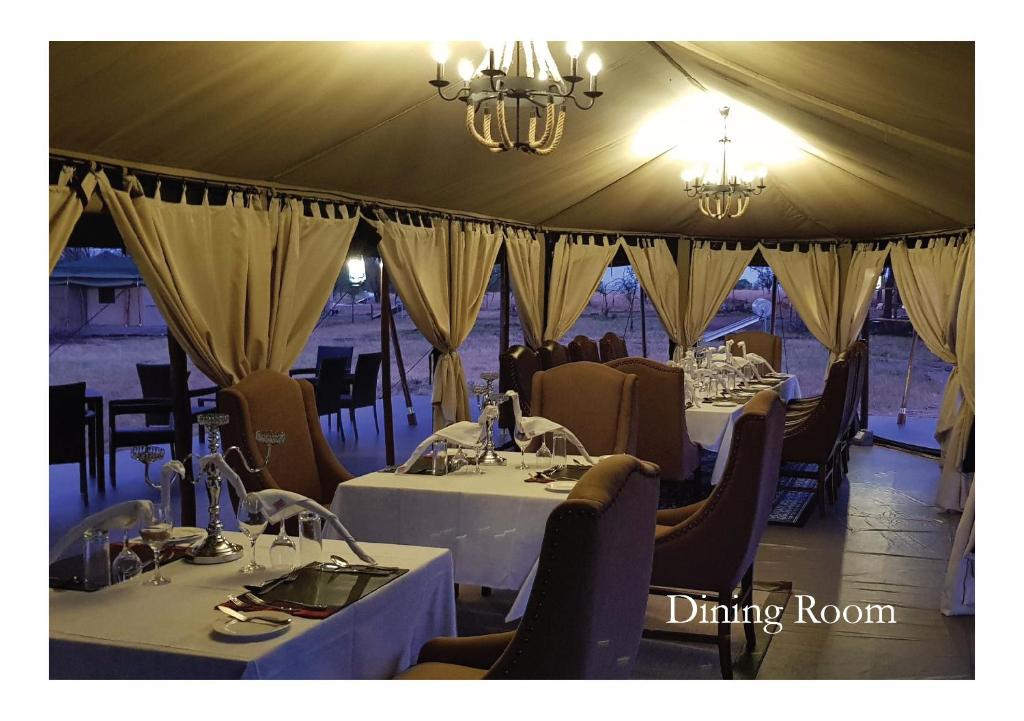 una tenda con sala da pranzo con tavoli e sedie. di OLE SERAI LUXURY CAMP - KOGATENDE a Nyanungu