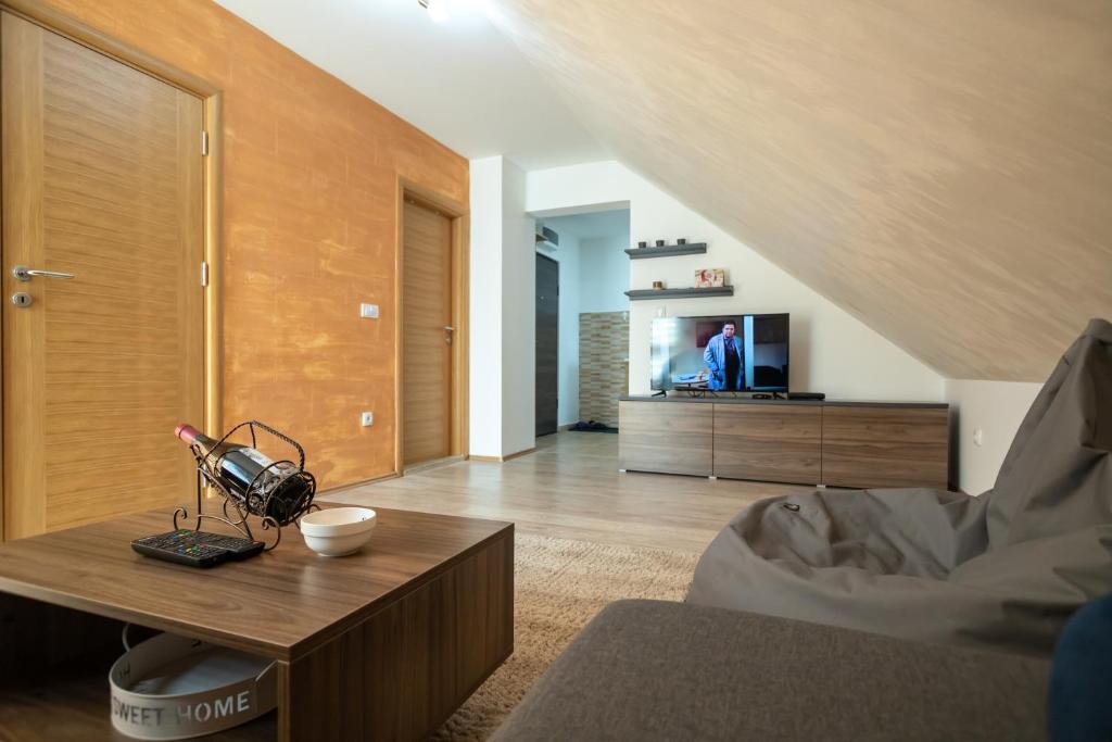 ein Wohnzimmer mit einem Tisch und einem TV in der Unterkunft Um Zlatibor in Zlatibor