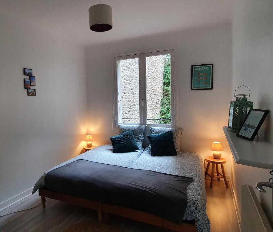 Un dormitorio con una cama con almohadas azules y una ventana en Chez Stella, en Audierne