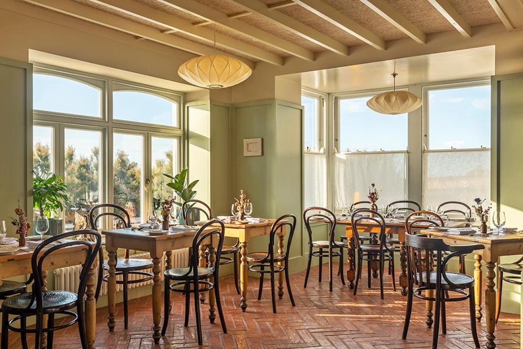 a dining room with tables and chairs and windows at Fort Road Hotel in Margate