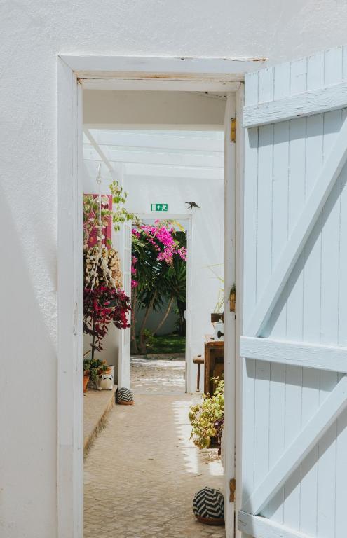 an open door to a garden with flowers at Senhora do Cabo Meco Homy Holidays in Sesimbra