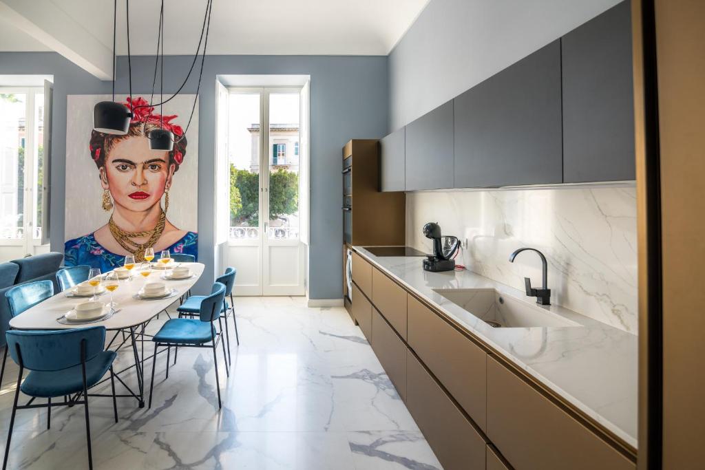 eine Küche mit einem Tisch und einem Bild einer Frau in der Unterkunft Frida apartments by Dimore in Sicily in Syrakus