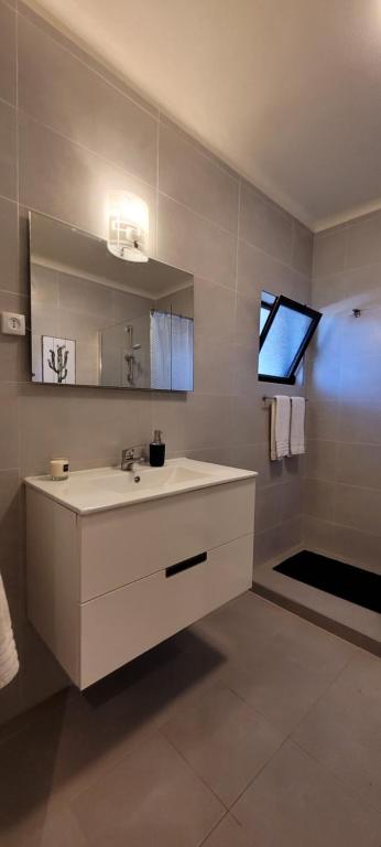 ein Badezimmer mit einem weißen Waschbecken und einem Spiegel in der Unterkunft Jardins da Falesia in Albufeira