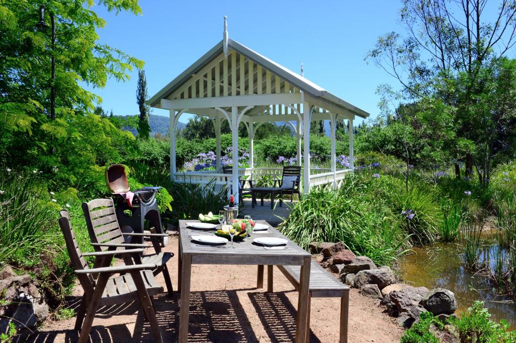 einen Tisch und Stühle in einem Garten mit Pavillon in der Unterkunft Crystal Creek Meadows in Kangaroo Valley