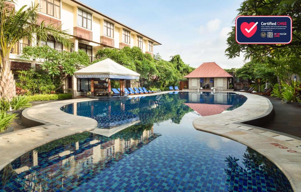 a swimming pool in front of a building at Best Western Resort Kuta in Kuta
