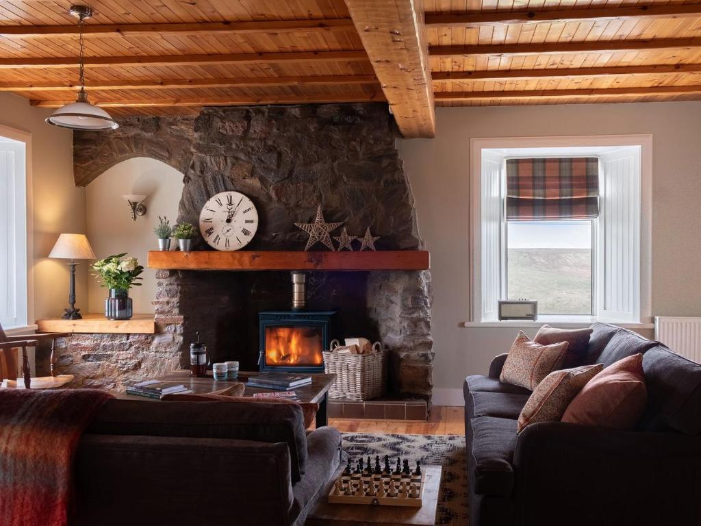 a living room with a stone wall with a fireplace at High Ranachan in Campbeltown