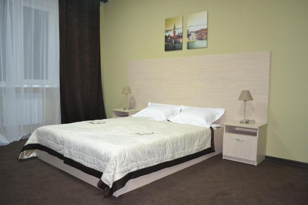 アルザマスにあるHotel Kommersantのベッドルーム1室(大型ベッド1台、白いシーツ、枕付)