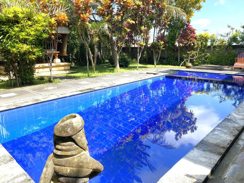 a swimming pool with a stone statue next to it at Villa Agung Khalia Ubud in Ubud
