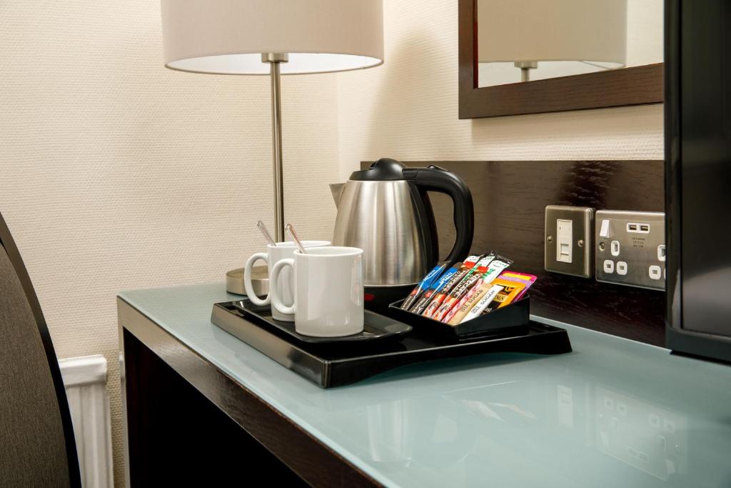 a table with a coffee pot and mugs on it at Mercure Glasgow City Hotel in Glasgow