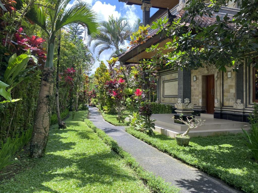 a garden with trees and flowers and a walkway at Villa Agung Khalia Ubud in Ubud