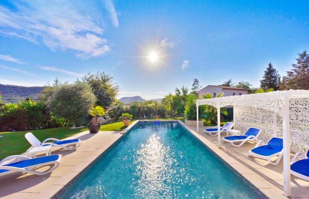 a swimming pool with chairs and a gazebo at Appartement Villa Quietude in Bagnols-en-Forêt