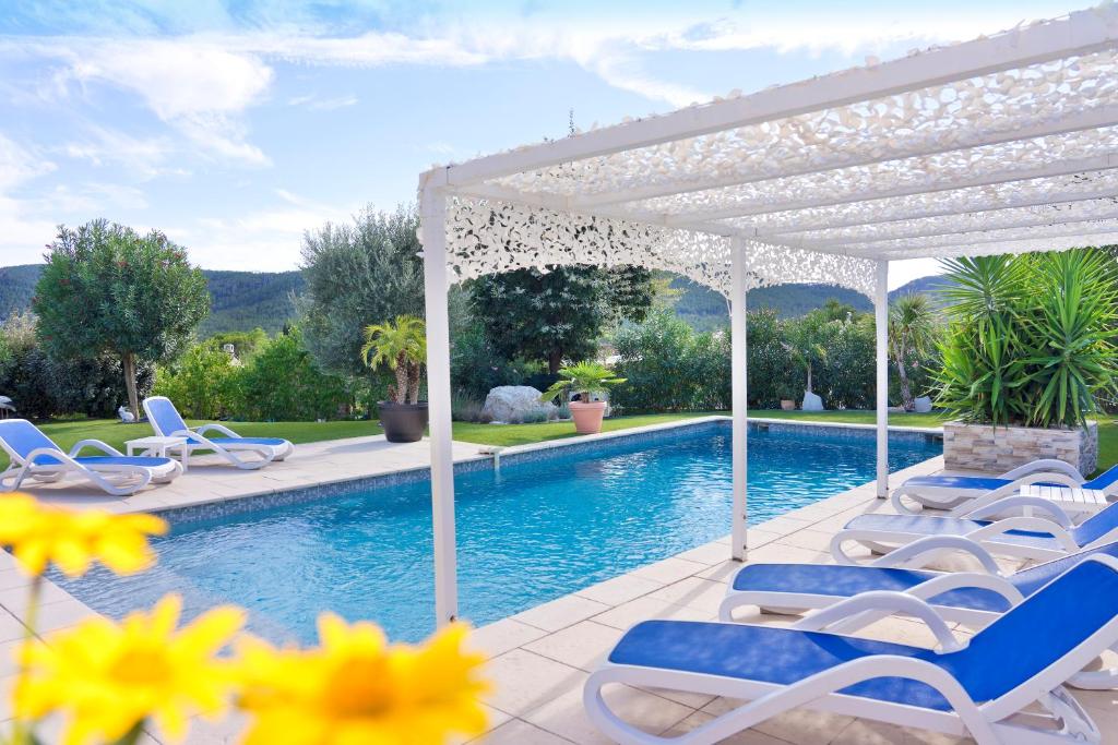 a swimming pool with chairs and a white pergola at Appartement Villa Quietude in Bagnols-en-Forêt