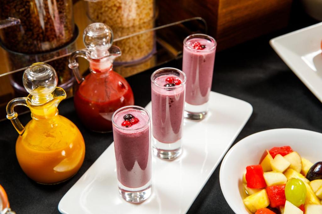 a table topped with three drinks and a bowl of fruit at Mercure Glasgow City Hotel in Glasgow
