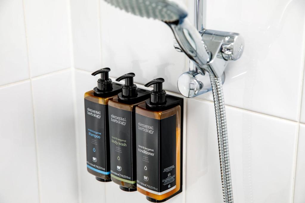 a group of three shampoo bottles on a rack in a bathroom at Mercure Glasgow City Hotel in Glasgow