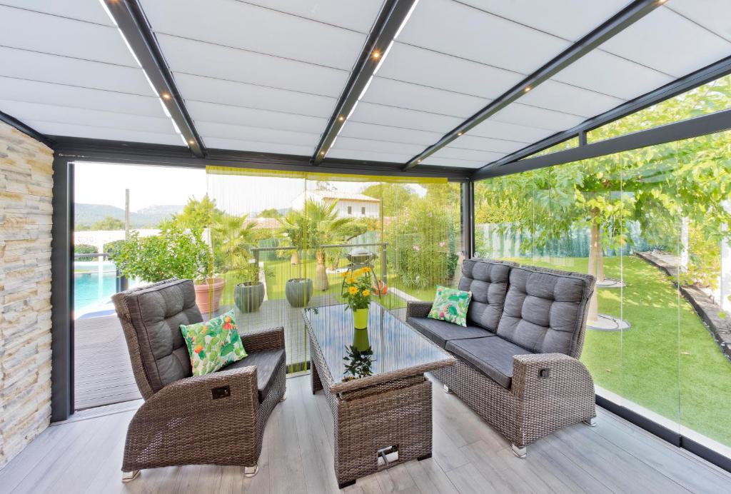 a conservatory with a table and chairs on a patio at Appartement Villa Quietude in Bagnols-en-Forêt