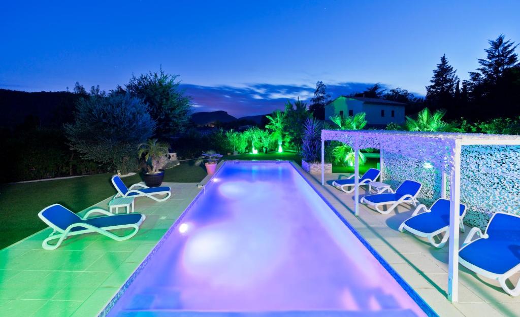 a swimming pool with lounge chairs next to a house at Appartement Villa Quietude in Bagnols-en-Forêt