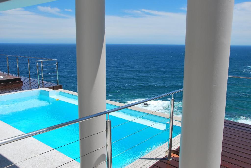 a balcony with a swimming pool and the ocean at Head over Hills in Knysna