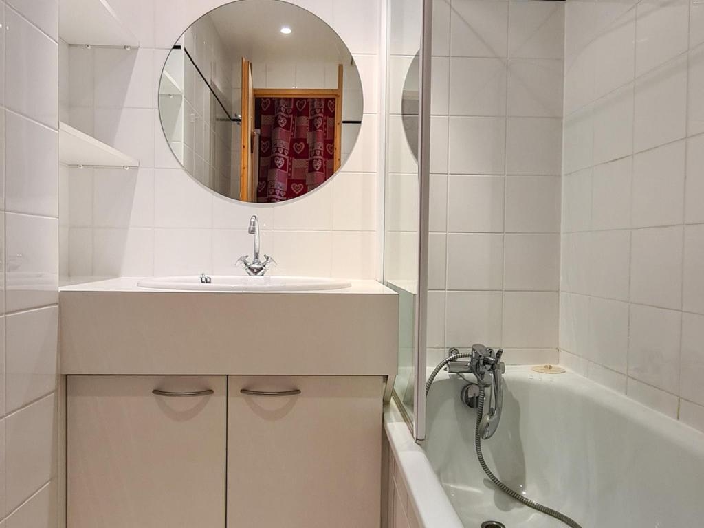 W łazience znajduje się umywalka, wanna i lustro. w obiekcie Studio rénové avec balcon sud, casier à ski, proche pistes et commerces - FR-1-425-156 w mieście Flaine