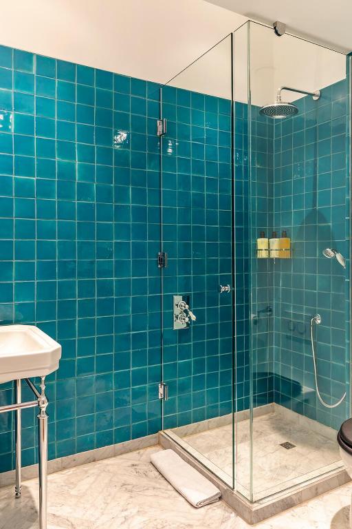 a blue tiled bathroom with a shower and a sink at Fort Road Hotel in Margate