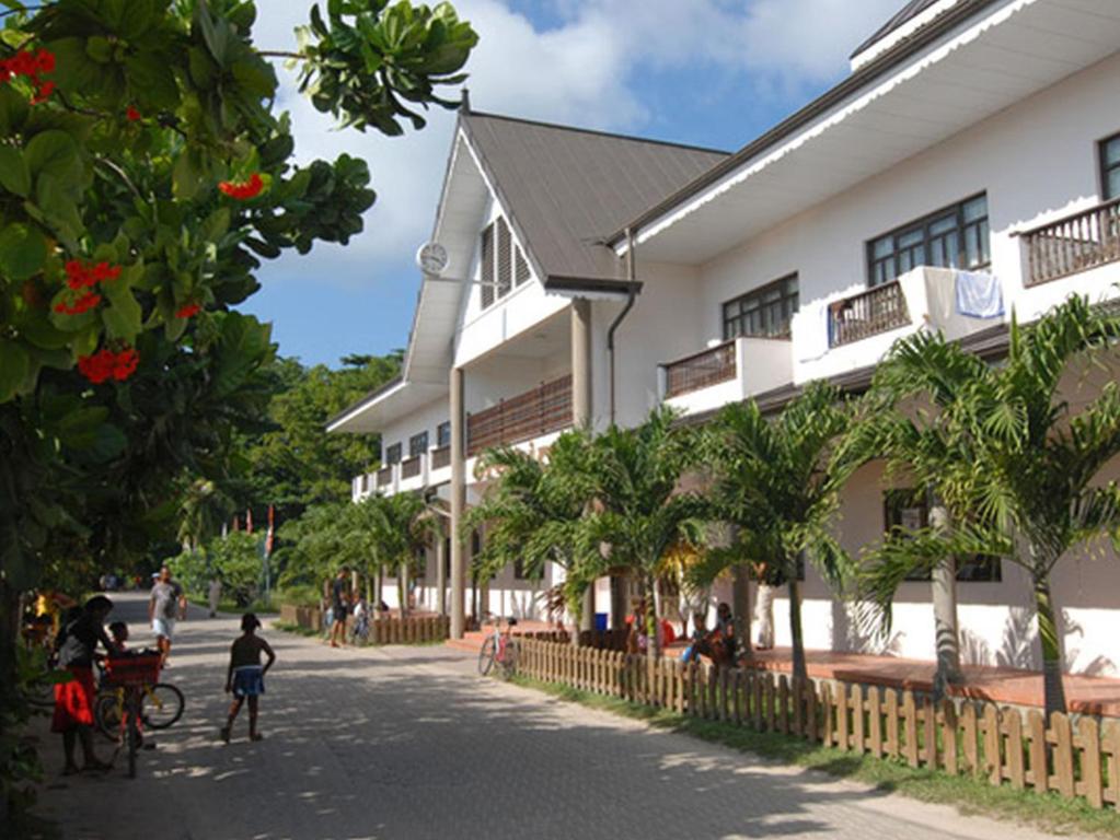 a building with people walking down a street in front of a building at Gregoire's Apartment in La Digue