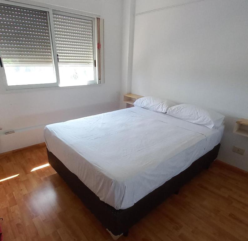 1 dormitorio con 1 cama con sábanas blancas y 2 ventanas en Vista Apart en Tigre