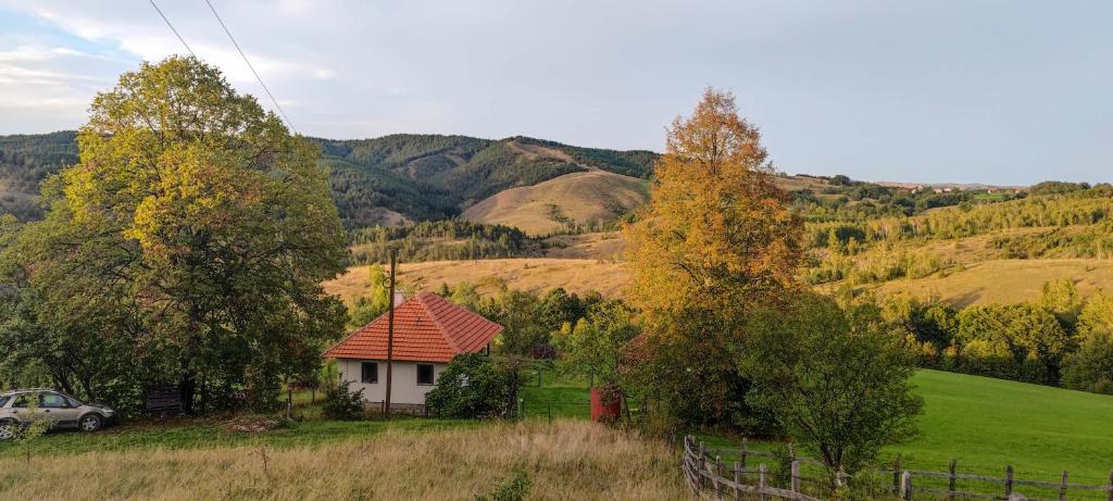 a small house in a field with trees and mountains at Studenac Mionica 