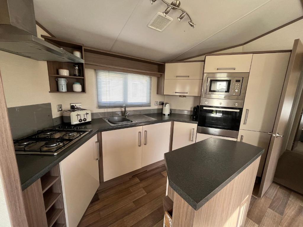 a kitchen with white cabinets and a black counter top at Fulmar 16, Scratby - California Cliffs, Parkdean, sleeps 6, pet friendly - 2 minutes from the beach! in Scratby