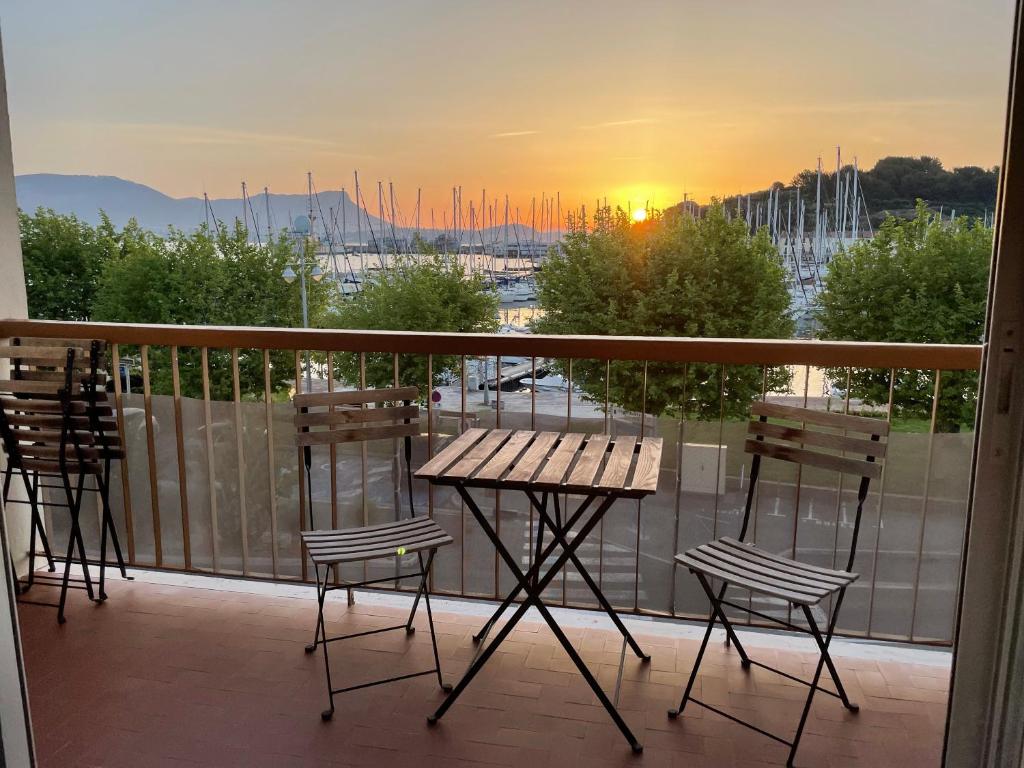 een balkon met een tafel en stoelen en de zonsondergang bij Appartement les pieds dans l'eau in Saint-Mandrier-sur-Mer