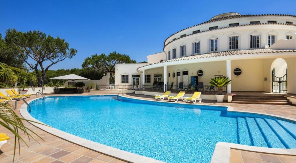 a swimming pool in front of a house at Beautiful 2-Bed Apartment golf pool beach in Faro
