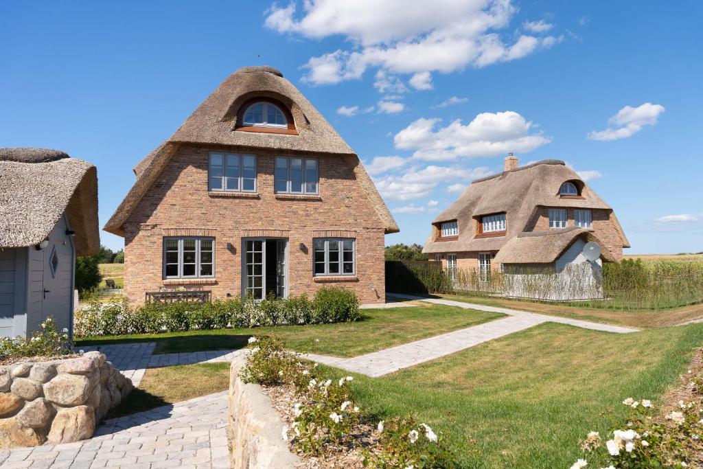 a house with a thatched roof and a pathway at Haus Deichblick 2 in Dunsum