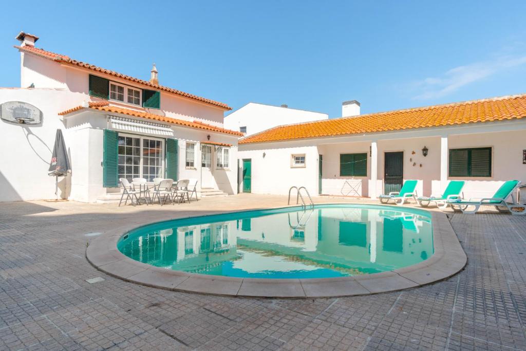 a swimming pool in a courtyard with a house at Villa Praia Nova in Almada