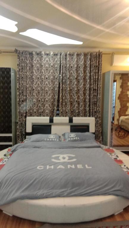 a bedroom with a large bed with a grey comforter at Мтко-1 in Khujand