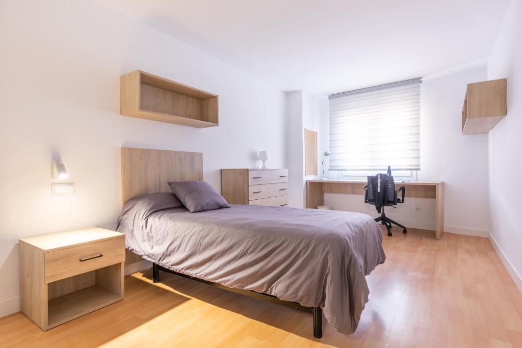 a bedroom with a bed and a desk and a television at Micampus Leganés in Leganés